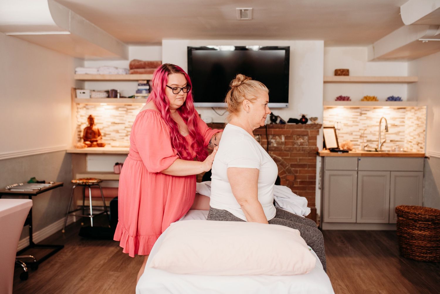 Healer in coral dress providing therapeutic treatment on massage table.