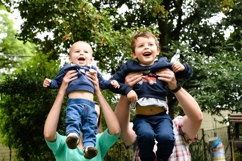 Parents throwing children in the air at a family photo shoot at their home