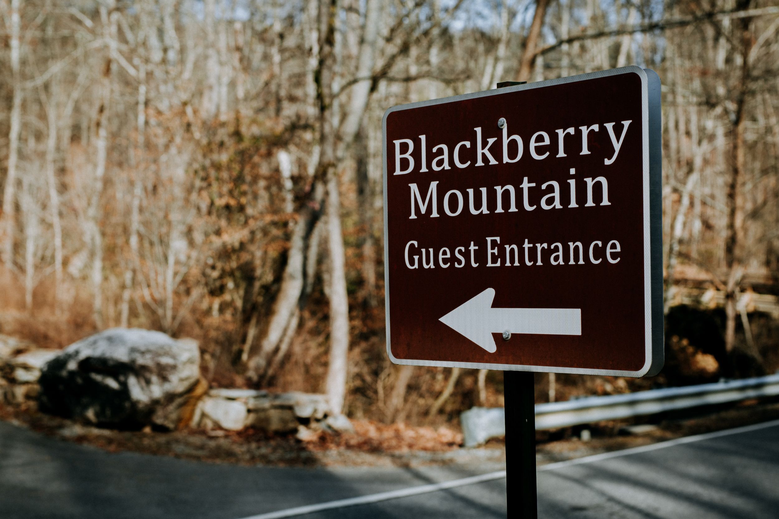 Brown directional sign for Blackberry Mountain Guest Entrance with an arrow pointing left.