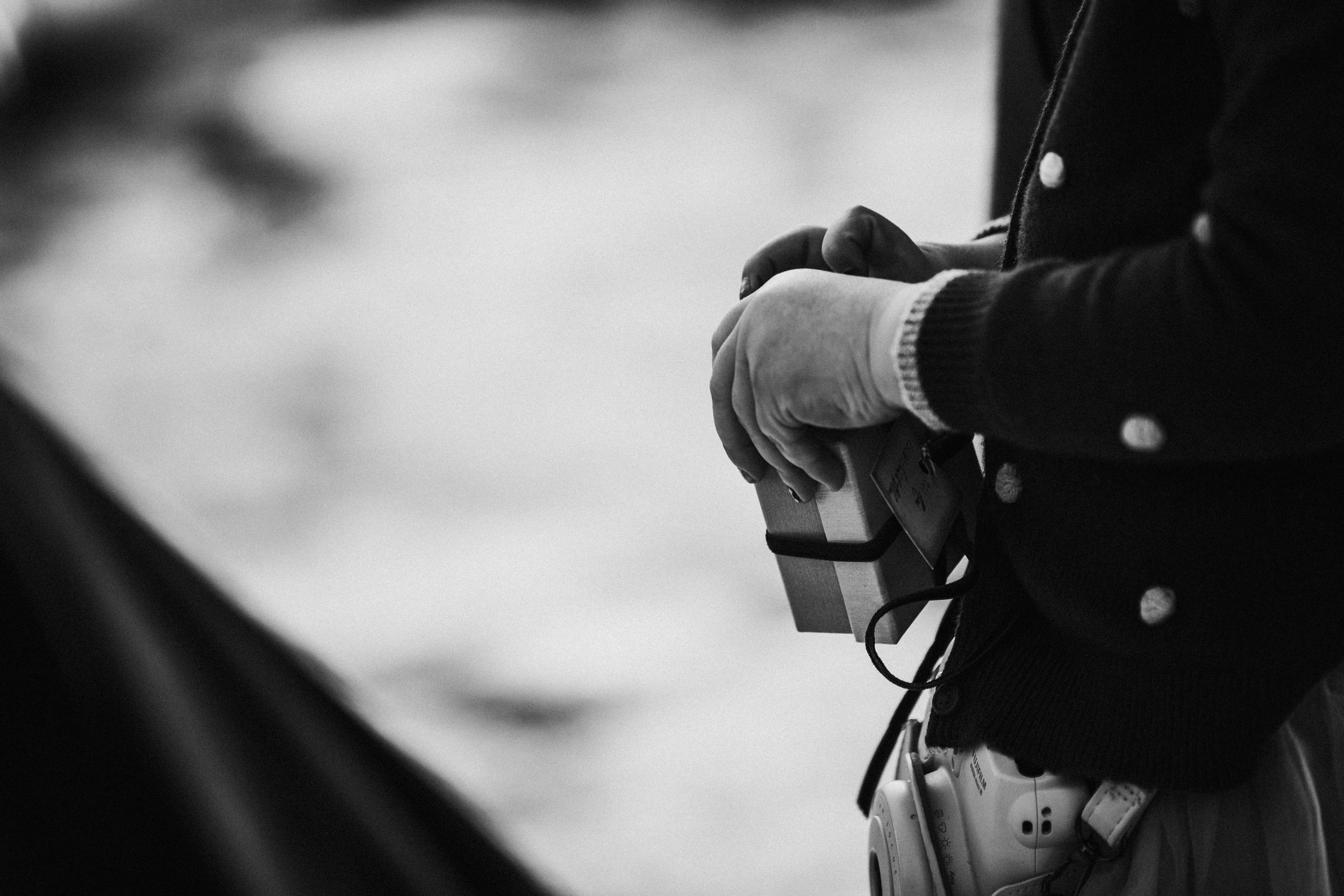 Black and white close-up photo of hands holding camera equipment in winter.
