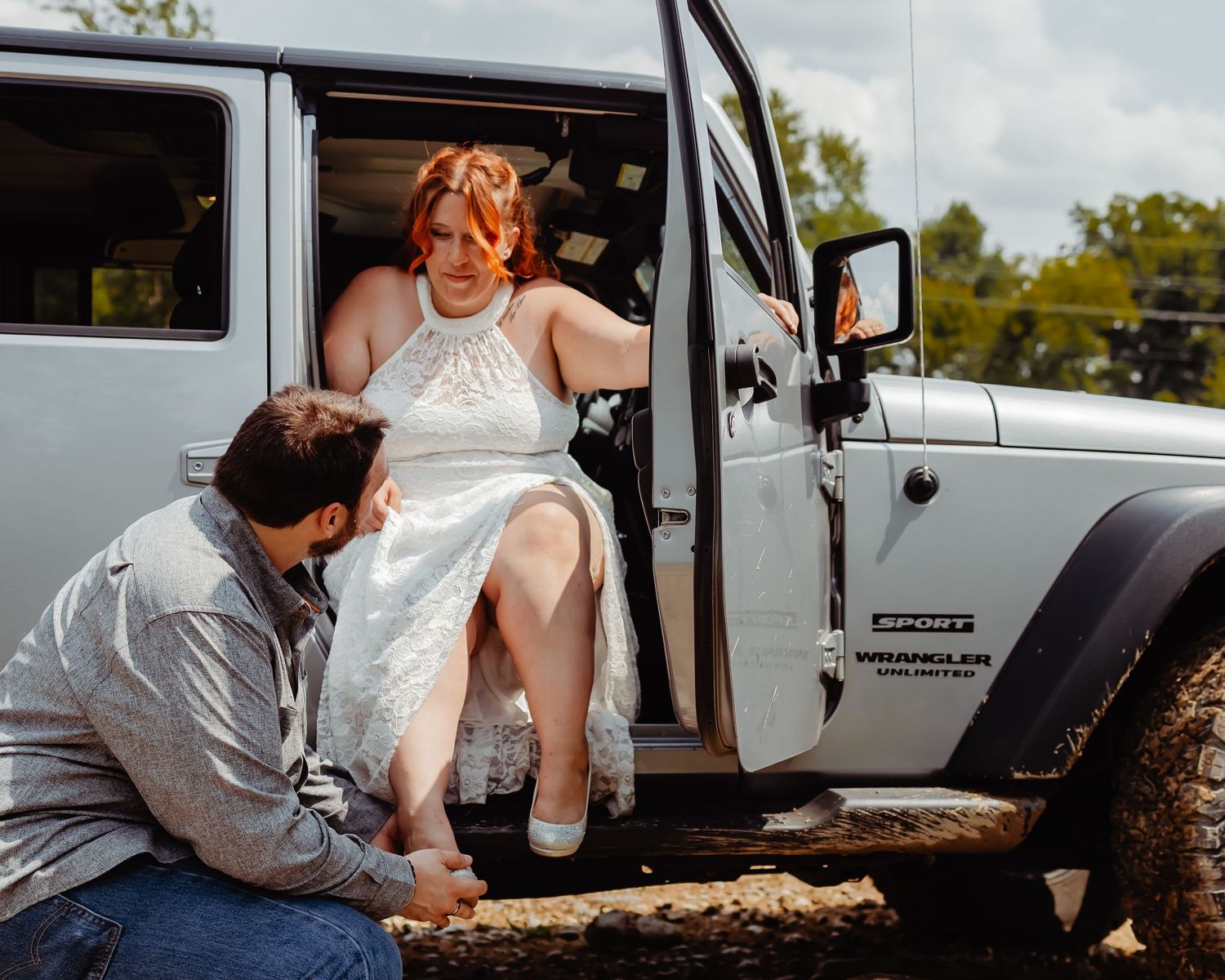A tender moment captured as a couple gets into a white Jeep on their wedding day.