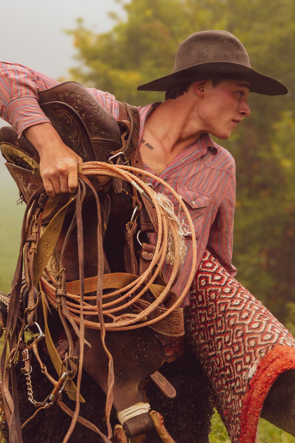 Detailed view of a brown leather saddle with decorative stitching and coiled lasso rope.