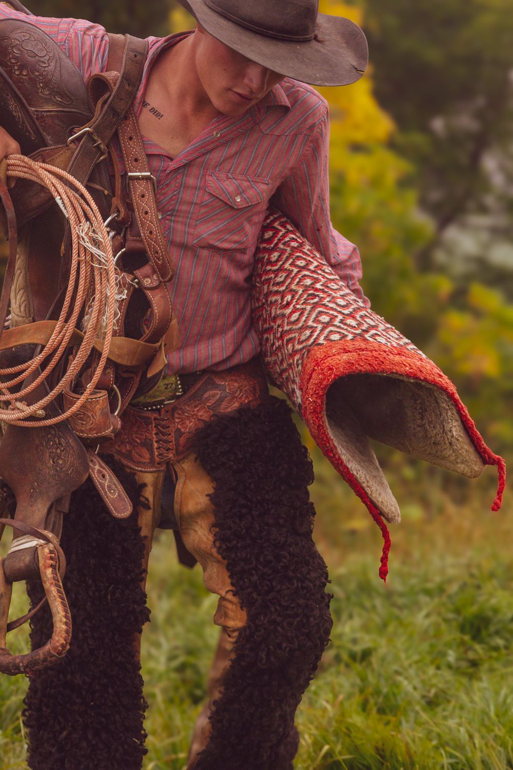 Detail shot of red bandana and western boots with leather saddle in outdoor setting.