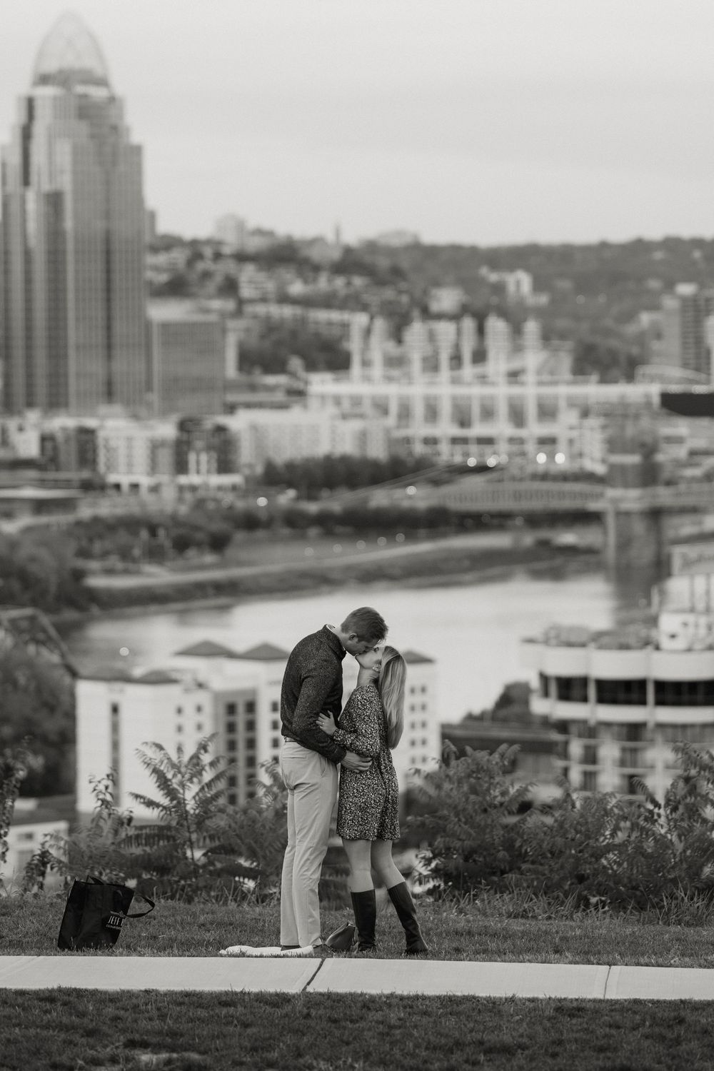 A black and white photo sequence shows someone taking photographs of a cityscape from an elevated vantage point.