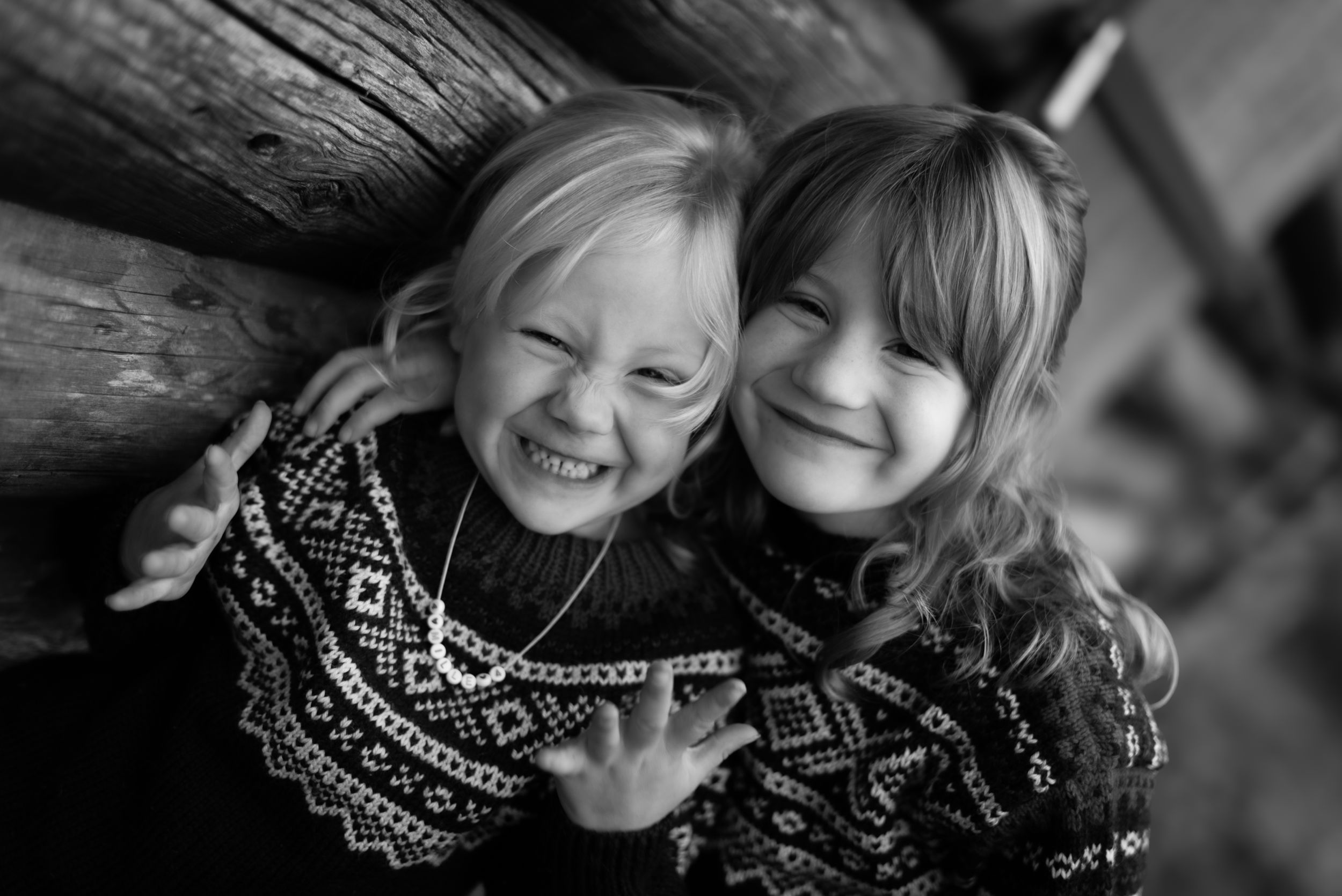 Black and white photo of two children in matching sweaters sharing laughter.