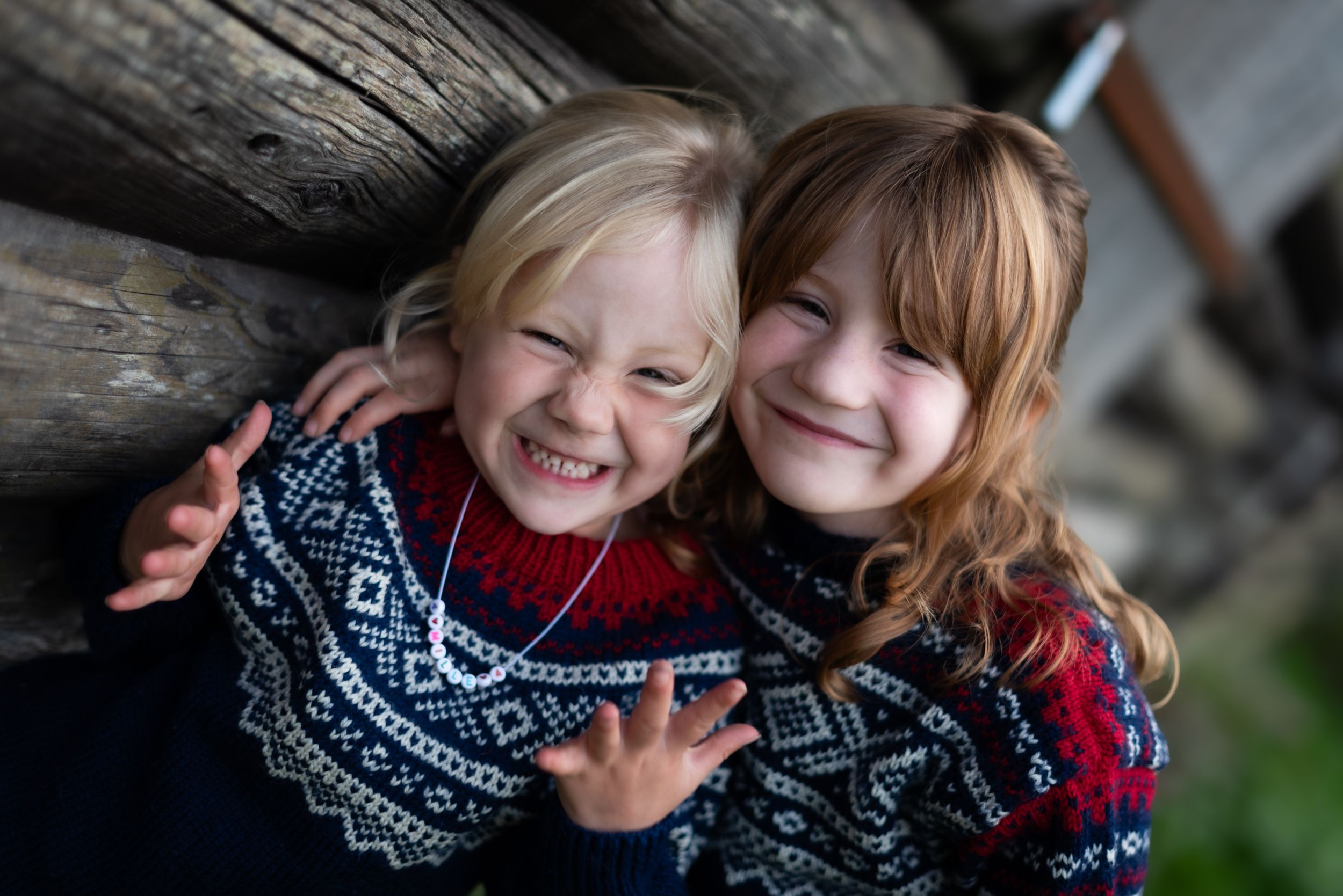 Two children in matching Nordic sweaters sharing joyful moment together.