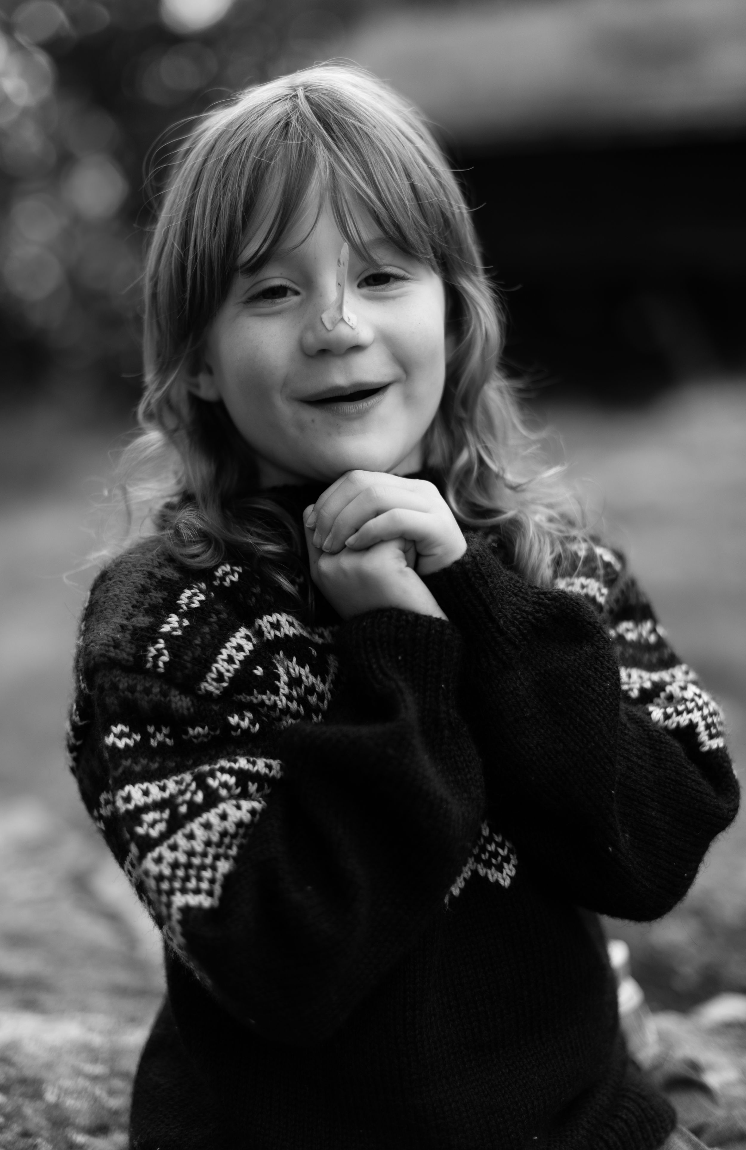 Black and white portrait of child in patterned sweater with playful expression.