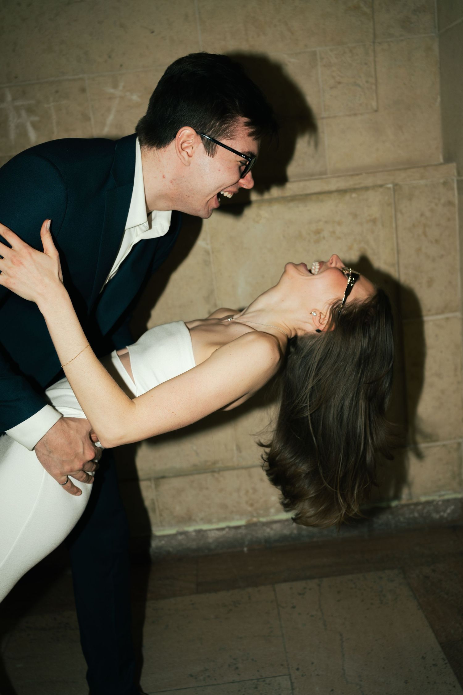 Dramatic dip pose captured against a concrete wall in an artistic style.