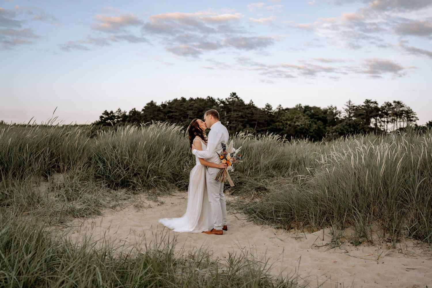A dreamy sunset wedding portrait in tall grass with moody sky backdrop.