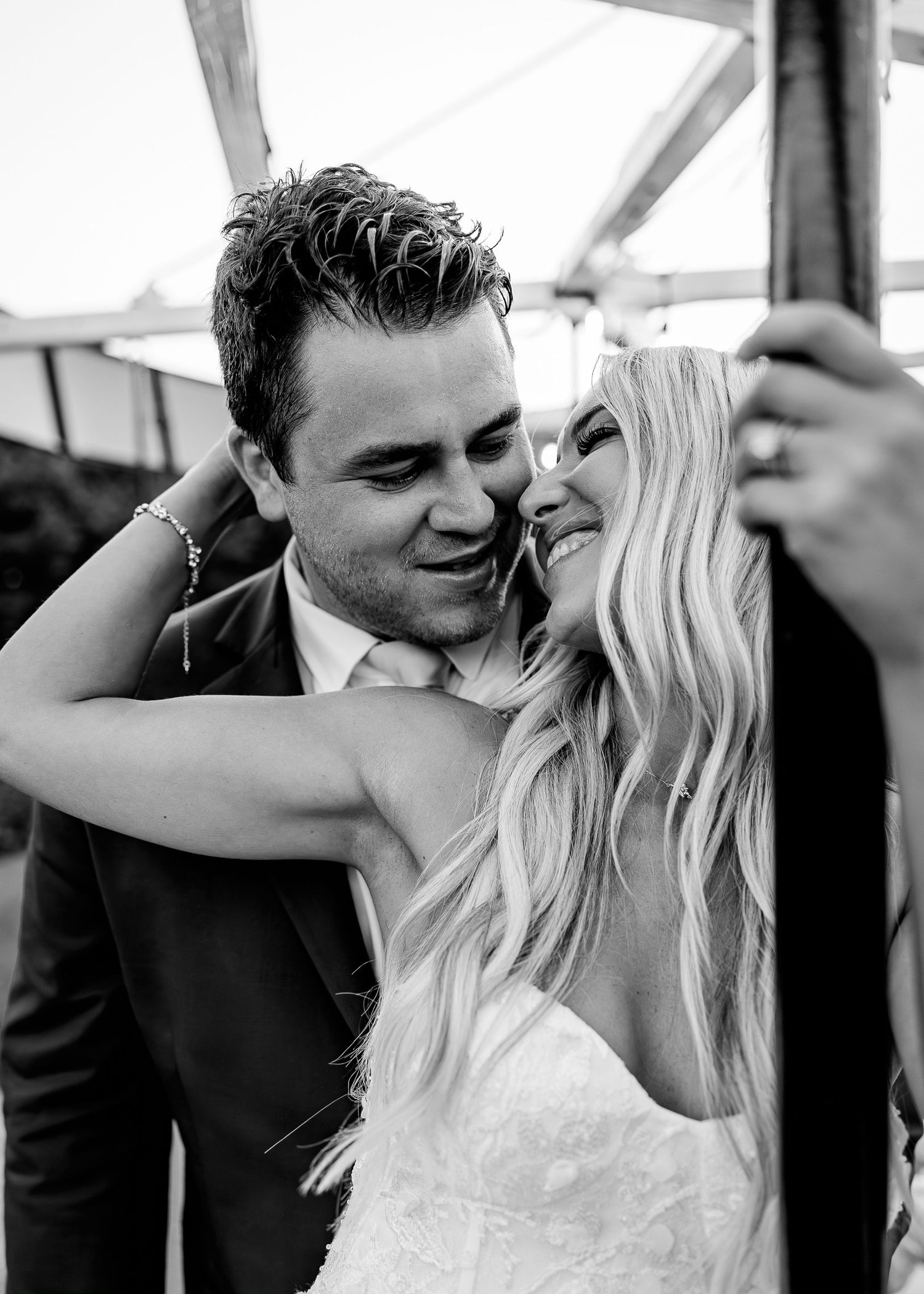 Happy couple sharing a special moment while cutting their two-tiered white wedding cake.