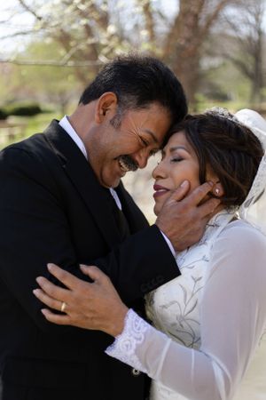 Sioux City, Iowa photographer. Joyful couple in wedding attire share an intimate moment, groom tenderly holding bride's face.