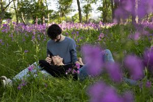 Sioux City, Iowa photographer. A couple lies together in a vibrant purple wildflower meadow, sharing a peaceful intimate moment.