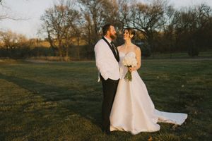 Sioux City, Iowa photographer. Bride and groom stand together in a golden sunset field, gazing at each other in a serene outdoor setting.