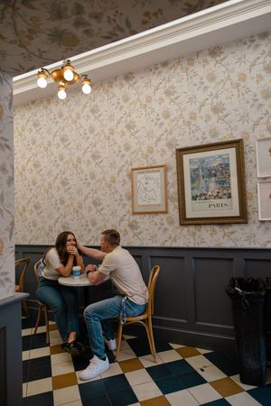 Sioux City, Iowa photographer. A couple shares a tender moment at a small cafe table with Parisian decor and checkered floors.