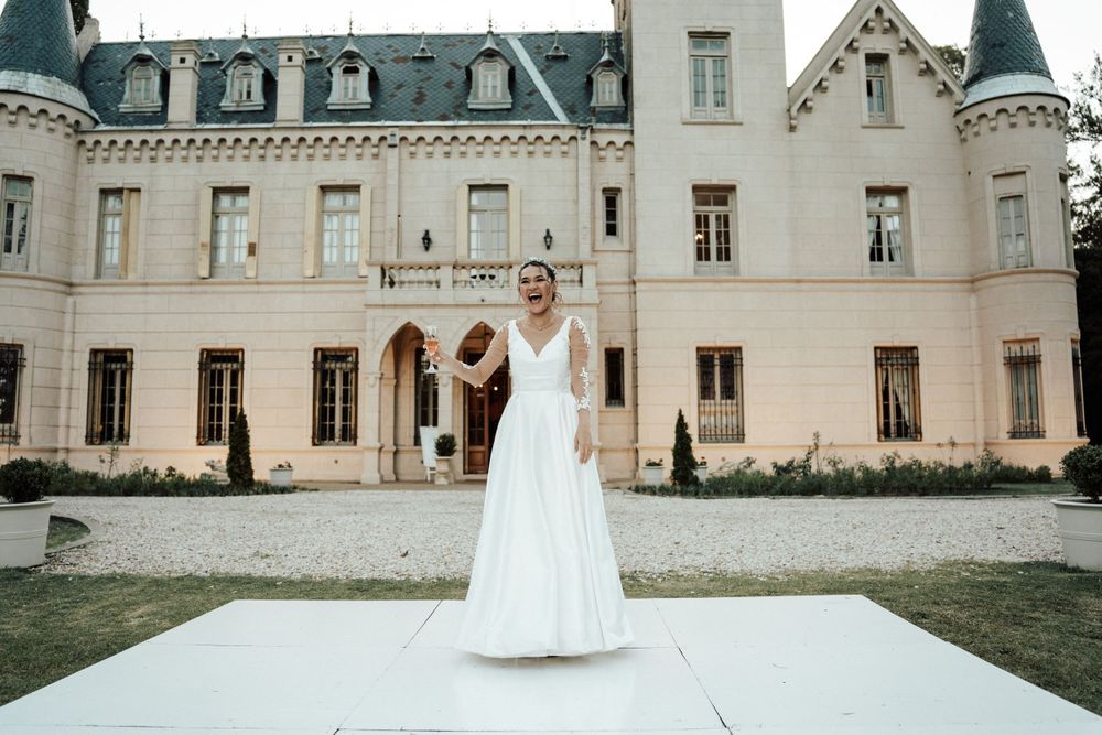 White wedding dress displayed in front of grand European-style chateau.