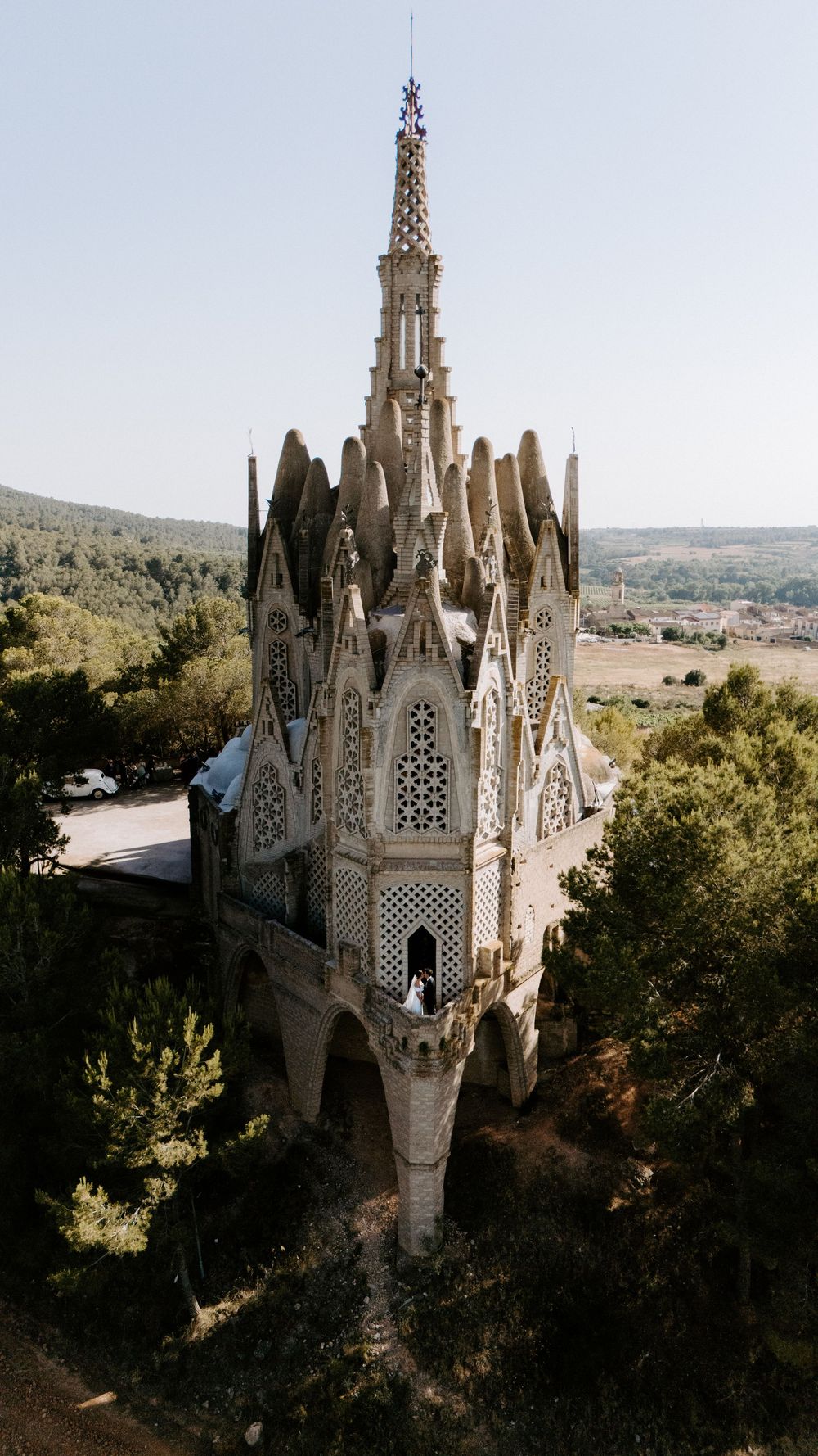 Gothic church spires rise above trees against a blue sky in Barcelona, showcasing ornate architectural details.