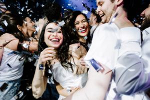 Joyful wedding reception celebration with confetti and dancing guests.