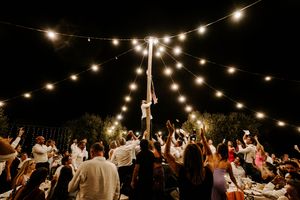 String lights create a magical atmosphere over an outdoor evening wedding reception. Mas Terrats