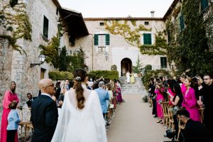 Wedding processional in charming stone courtyard with guests lining pathway.