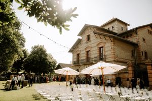 A panoramic view of a rustic stone venue with string lights and outdoor seating for a wedding ceremony. Masia Can Marti