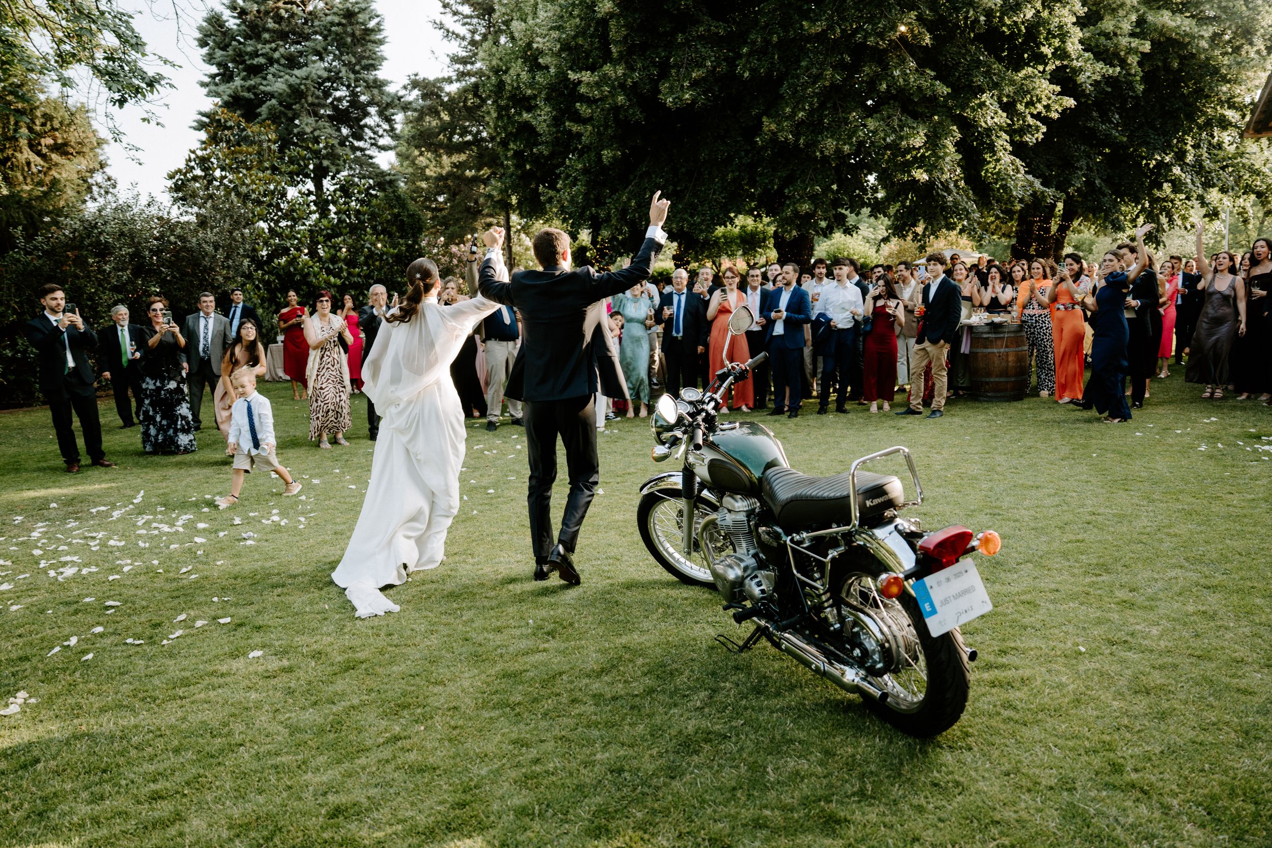 Wedding guests gather on a lush green lawn outside a historic building for an outdoor celebration. Masia Can Marti