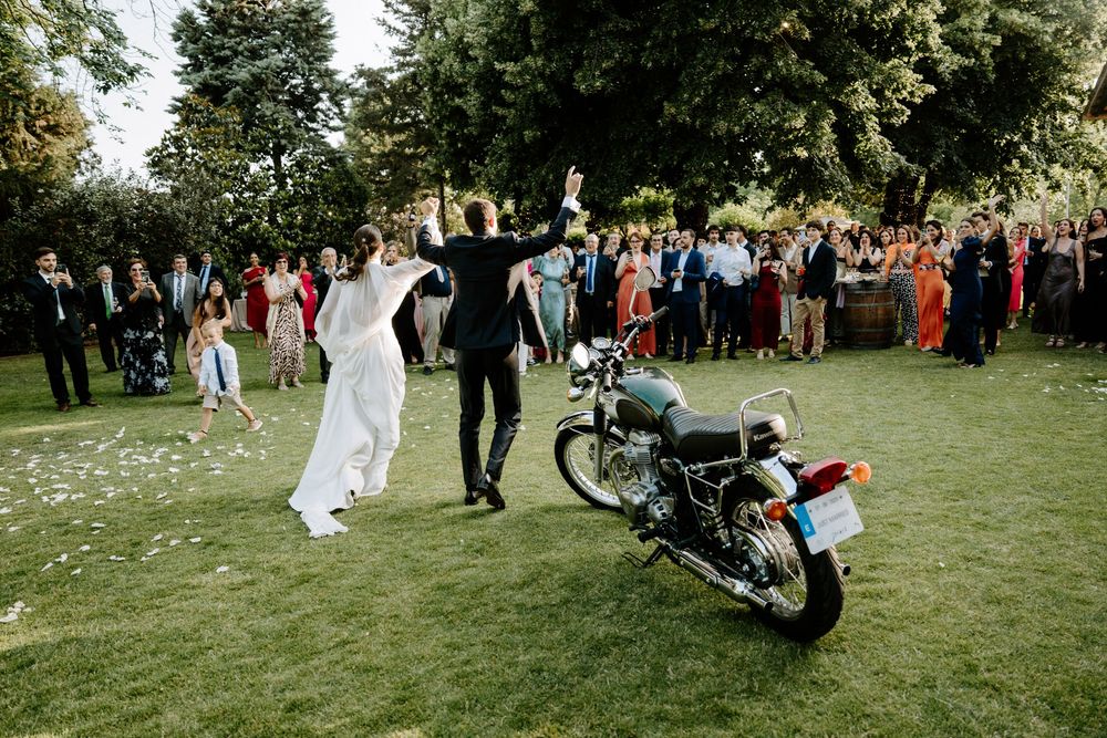 Wedding guests gather on a lush green lawn outside a historic building for an outdoor celebration. Masia Can Marti