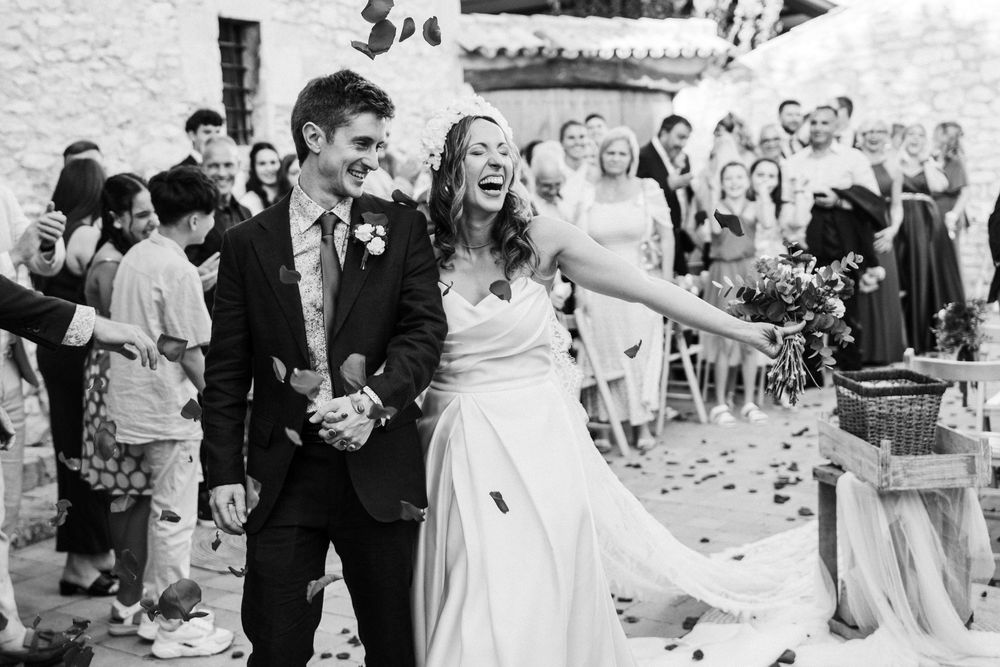 Wedding guests shower the happy couple with flower petals as they exit the church celebration.