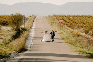Wedding couple walking down a scenic path surrounded by autumn foliage and natural landscapes.