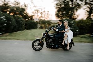 Wedding couple riding motorcycle at sunset for dramatic photo session.