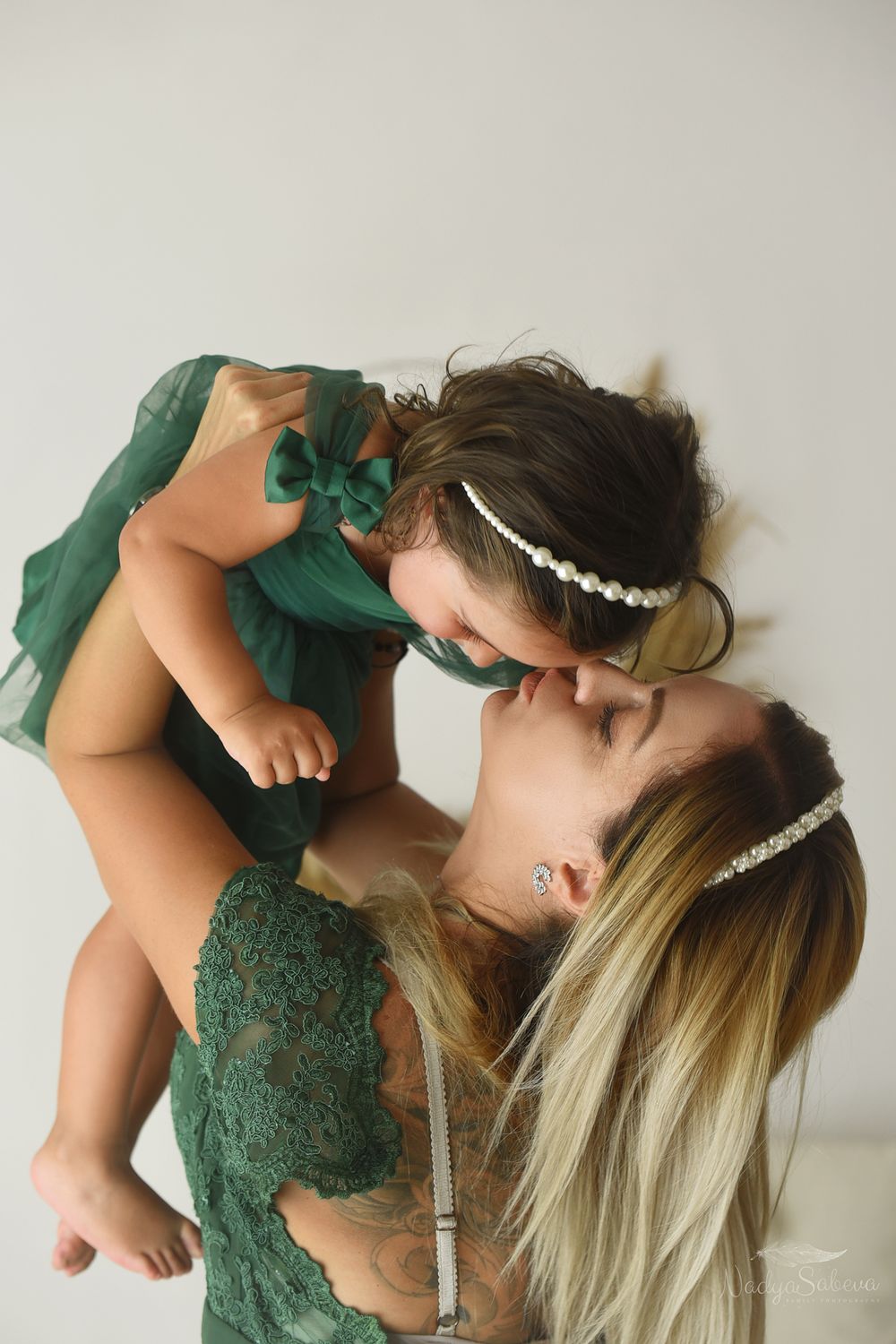 Sequence of four dynamic dance poses showing artistic movement in an emerald green lace dress against neutral backdrop.