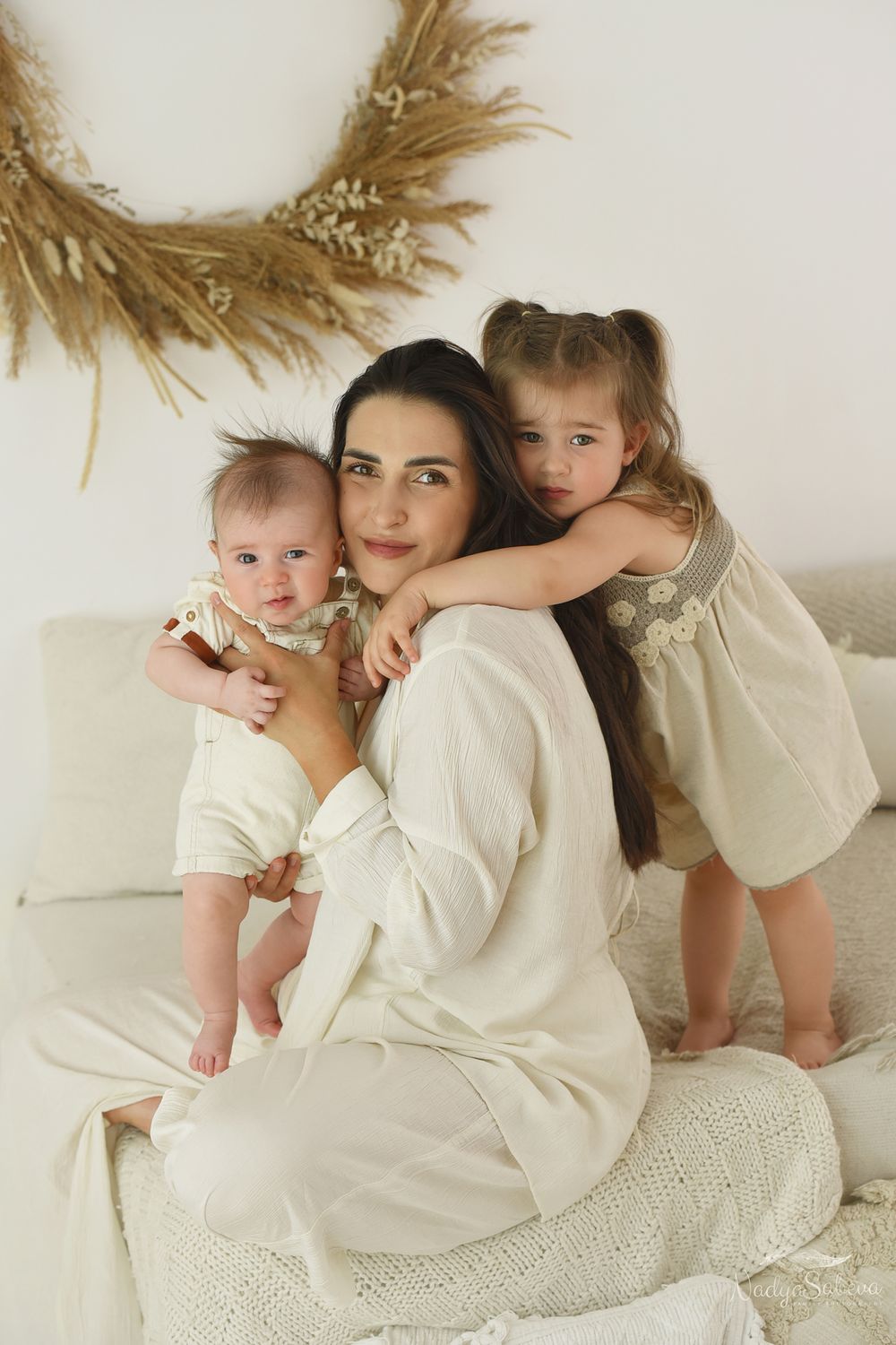 Family members wearing white clothing cuddle together on a cream-colored background in a series of connected photos.