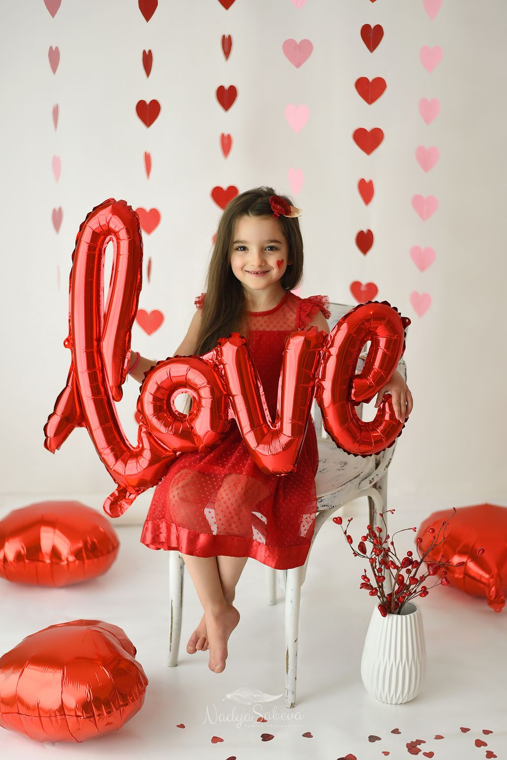Red heart balloons and decorations create a romantic Valentine's Day photo setup with white background.