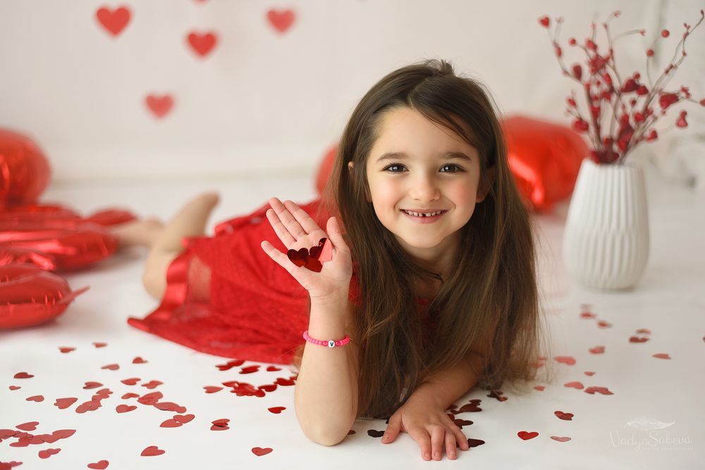 Valentine's day decorations with scattered red heart confetti on white surface and festive holiday decor.