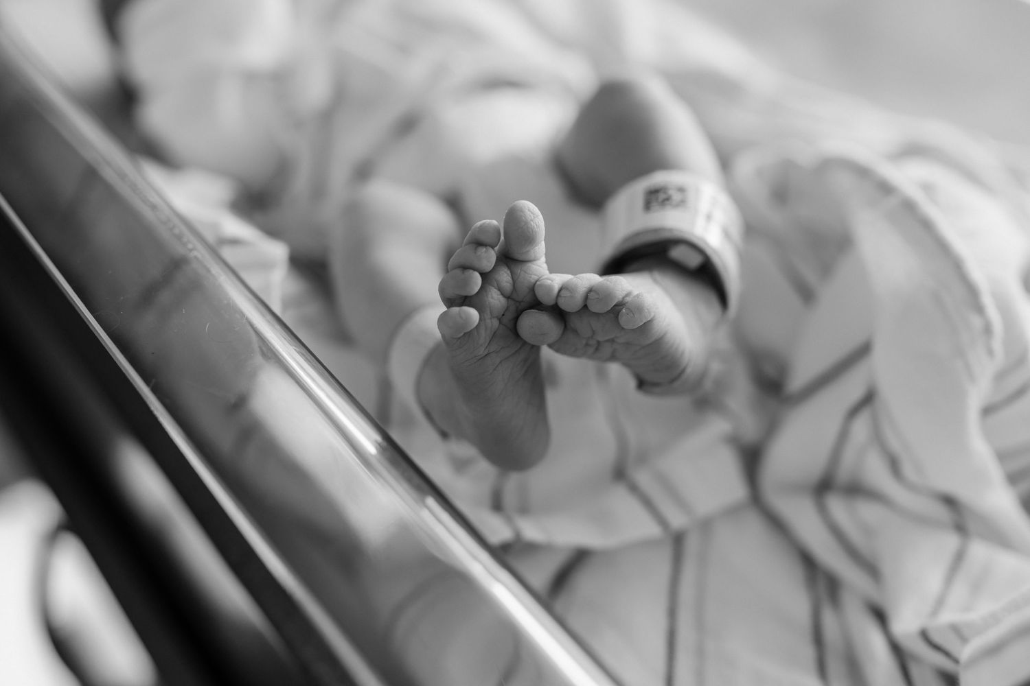 Black and white close-up of newborn baby feet in bassinet.