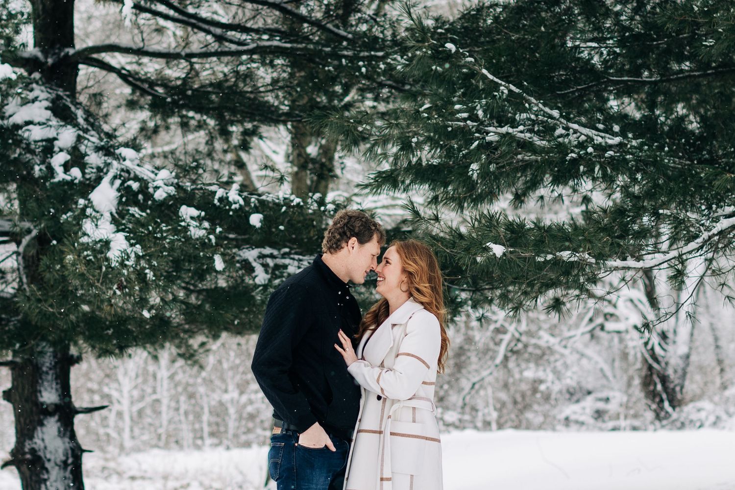 Intimate moment between couple in winter forest setting.