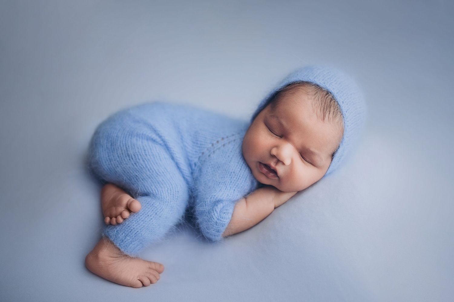 Newborn baby in a cute blue newborn knitted outfit  sleeping calmly
