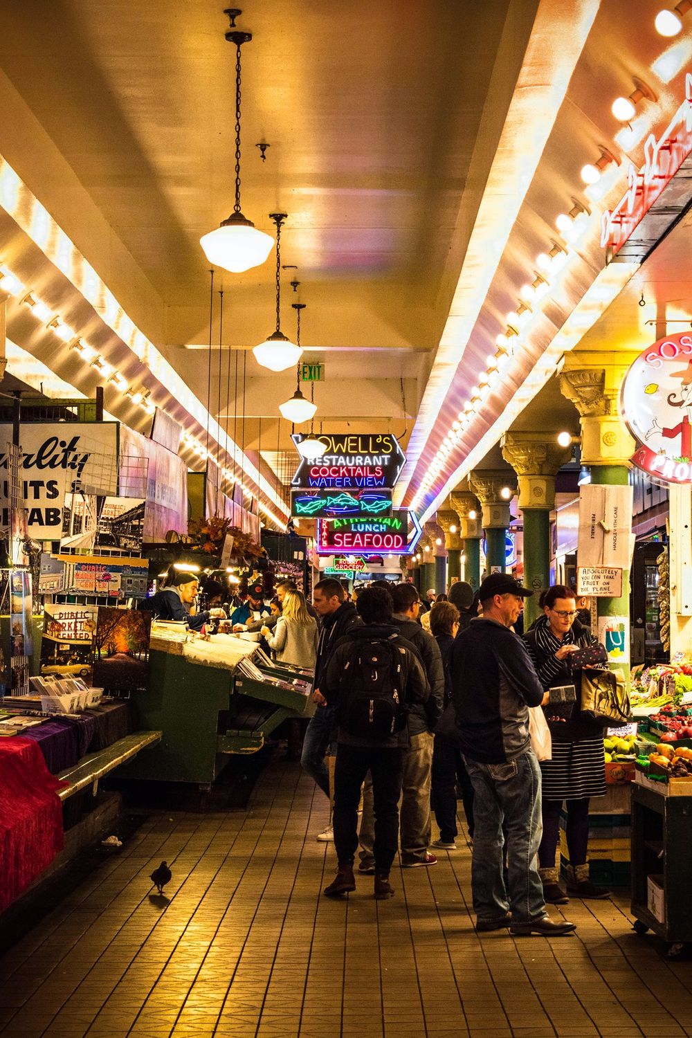 Bustling interior corridor of Pike Place Market with illuminated vendor stalls and shoppers.