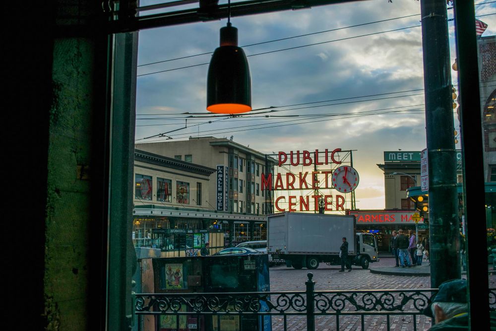 Public Market Center neon sign viewed through window at dusk.