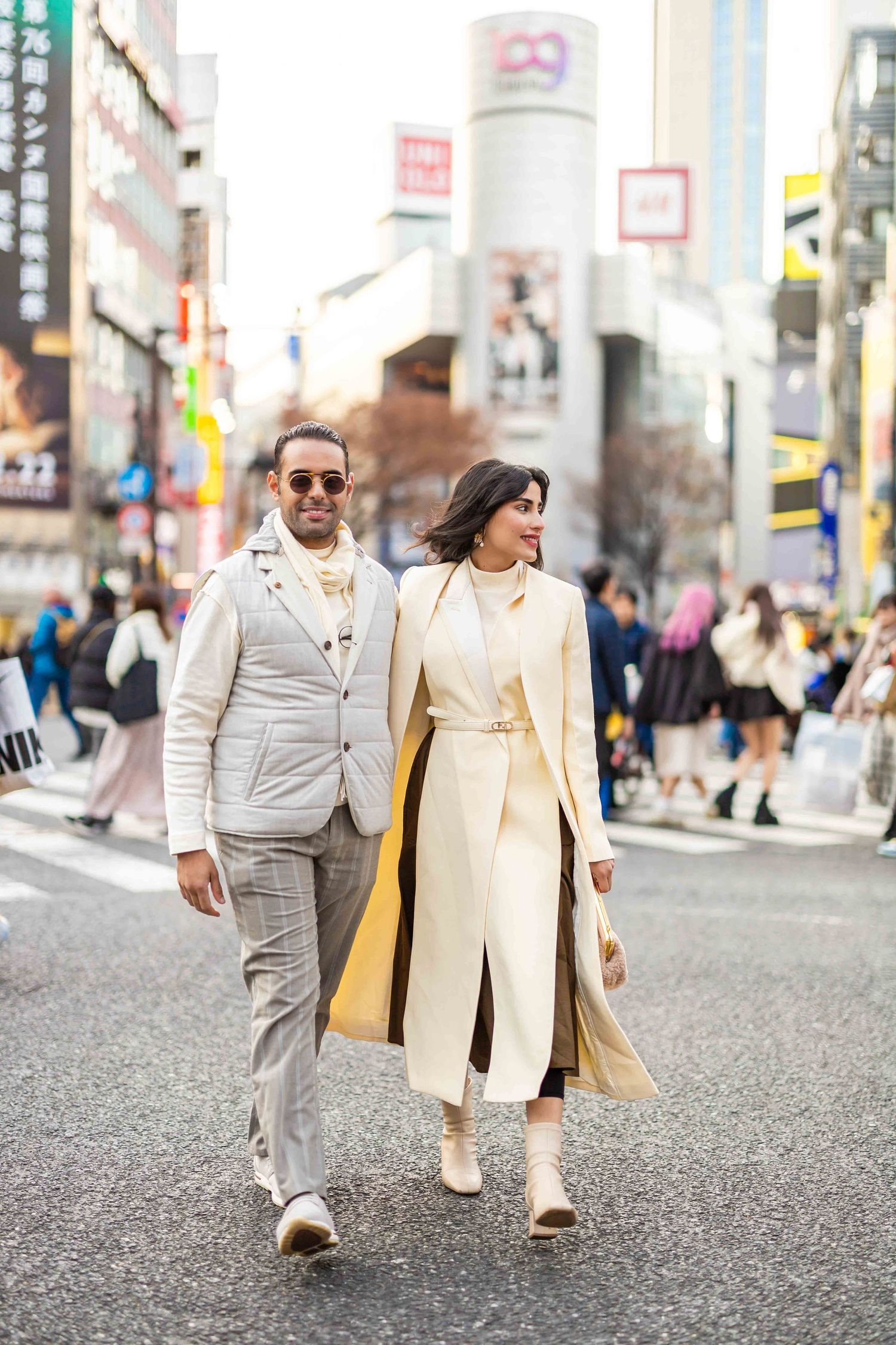 Stylish couple in light-colored outfits walking through the streets of Tokyo.