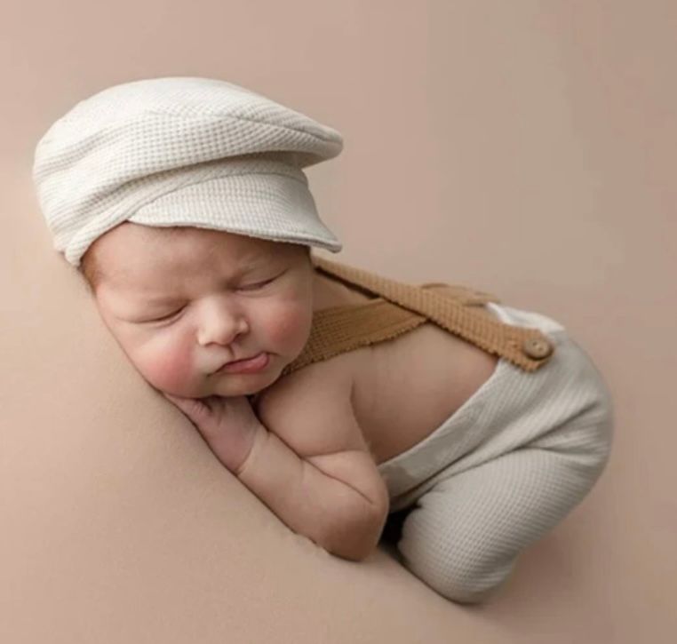 Minimalist newborn photography with white knit outfit against neutral backdrop.