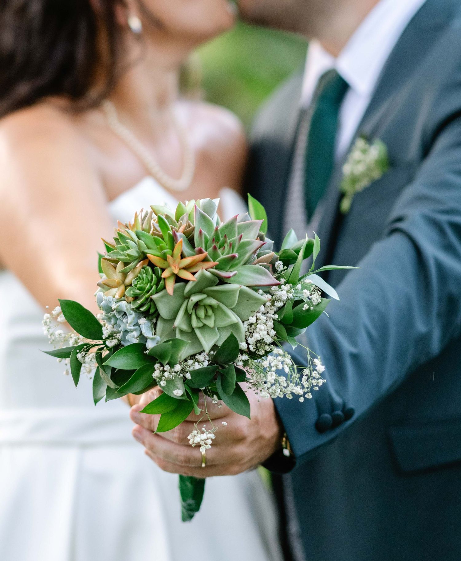 Bouquet de fleurs tendu par les mariés, veste verte et robe blanche en Guadeloupe