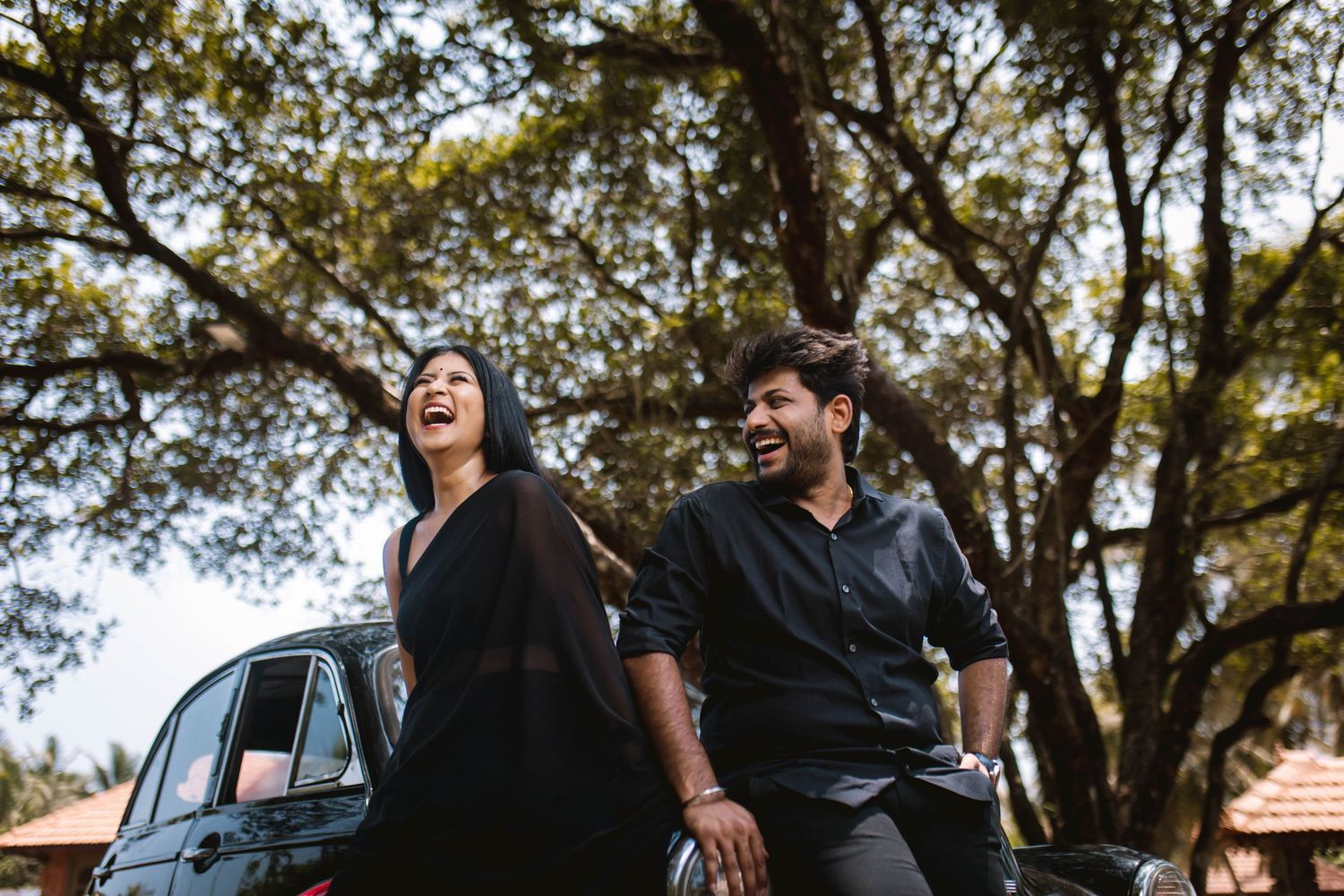 Two people share a joyful moment while walking together in a park setting with trees in the background.