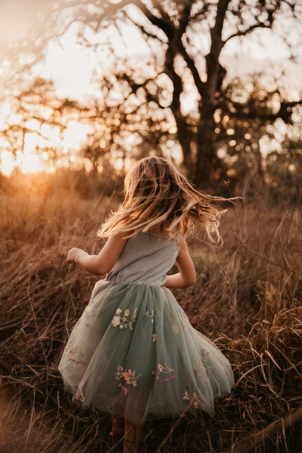 A dreamy scene of a flowing sage green dress twirling in a golden field at sunset.