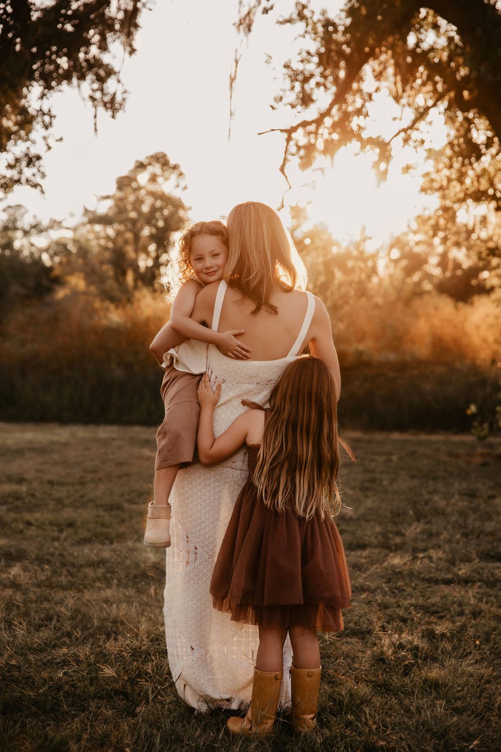 A tender embrace between mother and child at sunset in a golden Houston field creating a heartwarming silhouette.