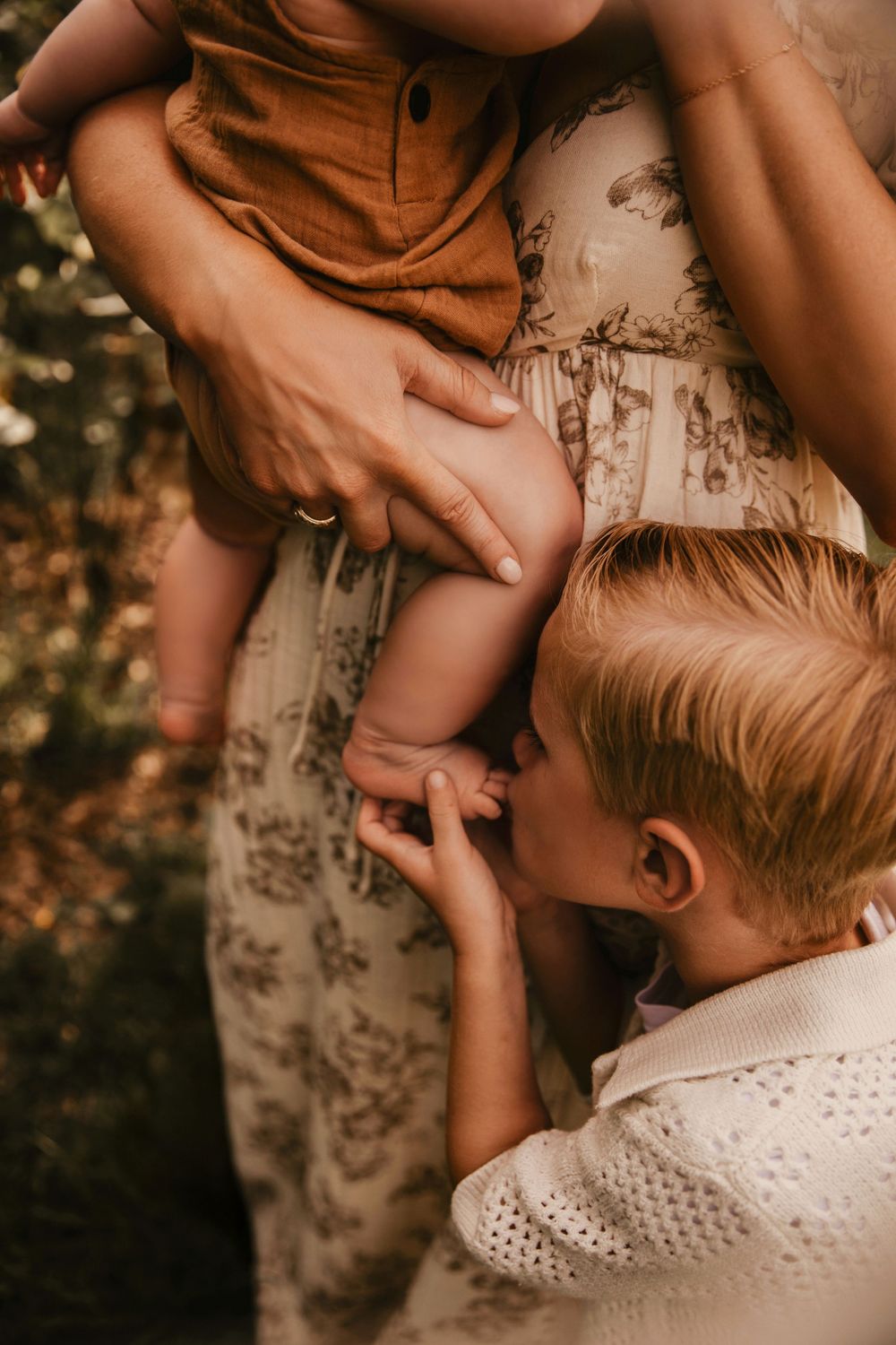 A tender moment captured in warm tones showing gentle sibling hands touching and embracing in soft natural lighting.