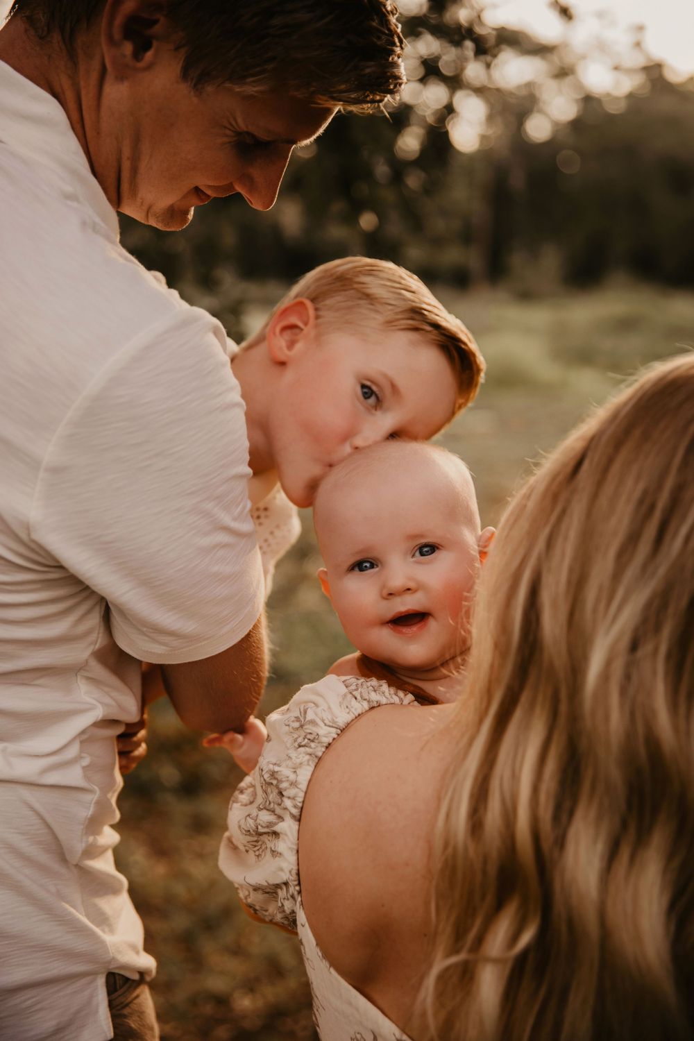 A family shares an intimate warm moment together outdoors during golden hour sunset.