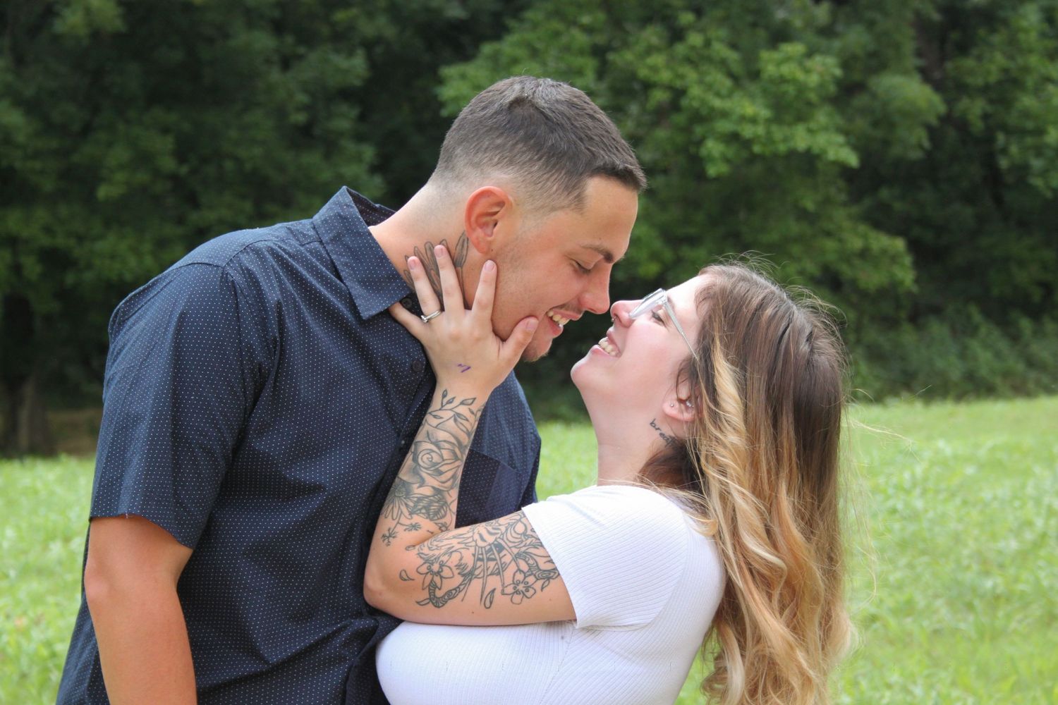 Husband and wife smiling at each other about to kiss at Stockstill park.