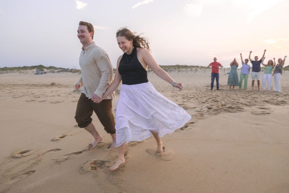 running engaged couple at the beach