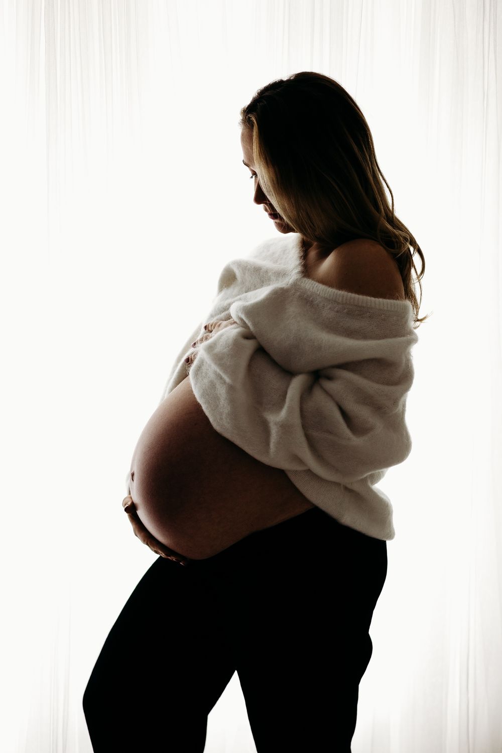 Mum-to-be standing in a soft-lit Nottingham photography studio maternity session.