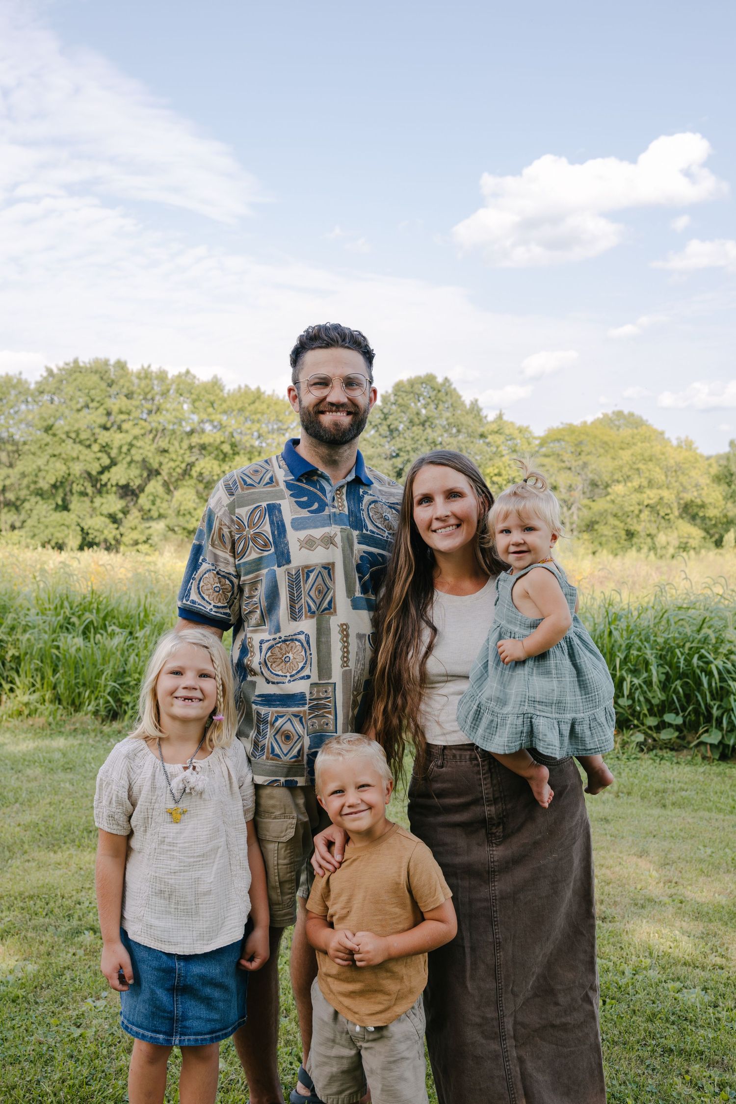 Family enjoying a sunny autumn day together by a hay bale in a rural field.